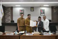 Gubernur Aceh Muzakir Manaf menerima draft revisi Undang-undang nomor 11 tahun 2006 tentang Pemerintahan Aceh dari Ketua Tim Revisi UUPA Tgk Anwar Ramli, di ruang serbaguna Dewan Perwakilan Rakyat Aceh, Senin (19/5/2025). Foto: Humas Aceh