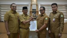 Penyerahan Surat Keputusan Pelaksana Tugas (Plt) Sekda Aceh kepada Taufik yang saat ini menjabat sebagai Kepala Dinas Perkim Aceh. Prosesi penyerahan SK tersebut berlangsung secara hybrid di dua tempat pada Senin (24/8/2026). Foto: Humas Aceh.